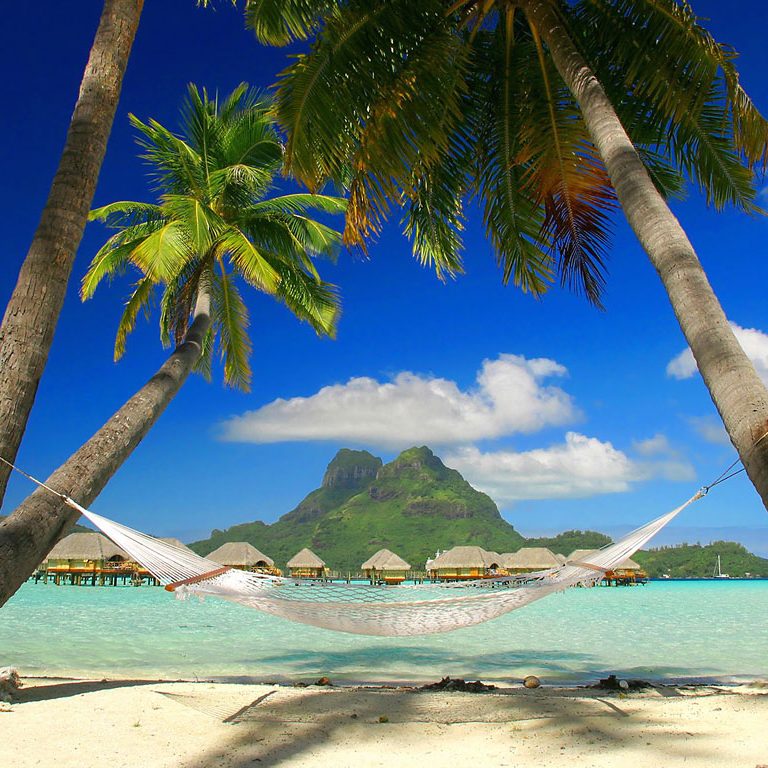 Tropical beach with overwater bungalows and turquoise lagoon